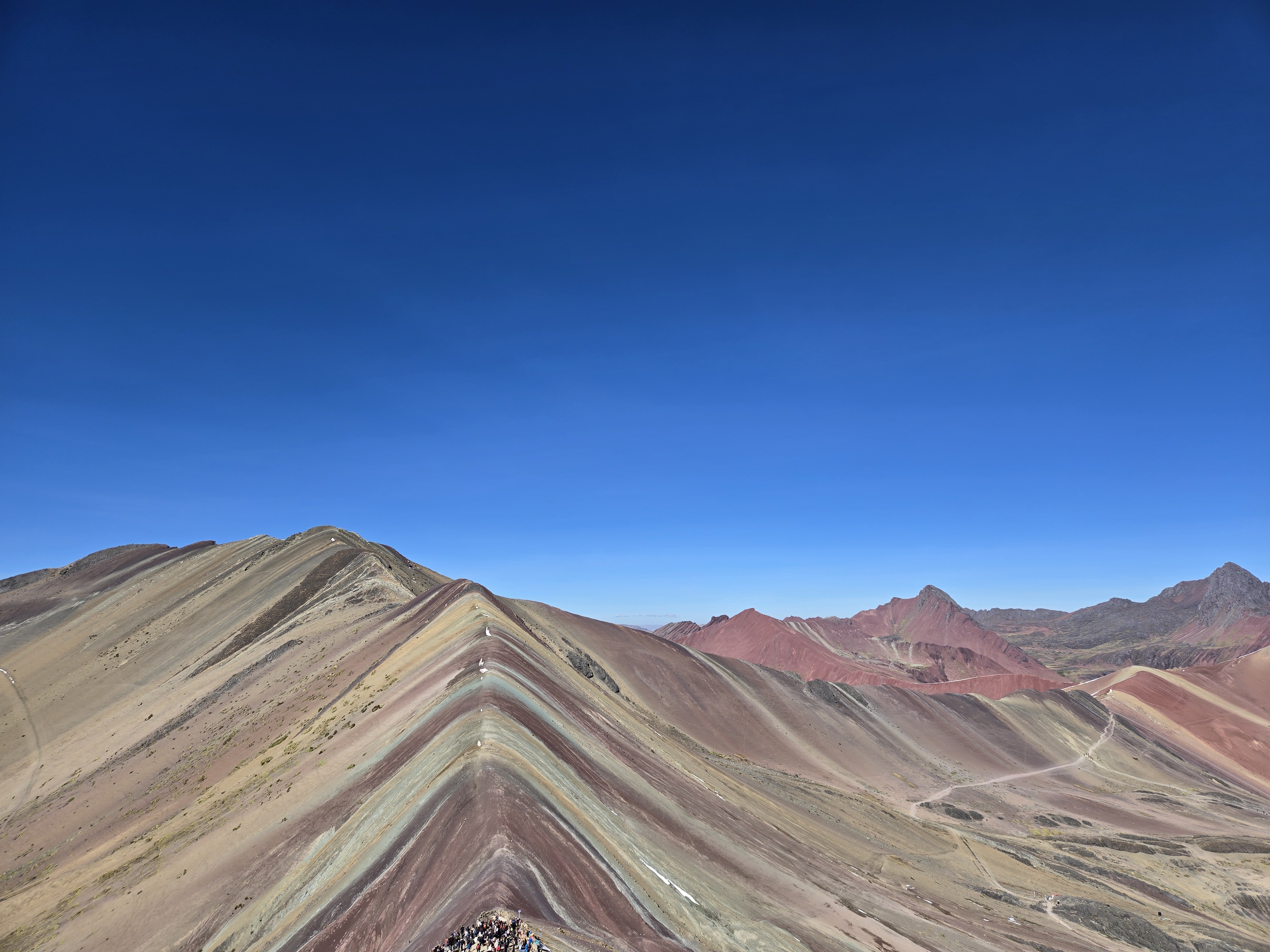 The colorful mineral layers of Rainbow Mountain beneath a blue sky